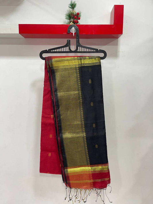 Colorful saree with black, red, and green pattern on a hanger against a white wall.