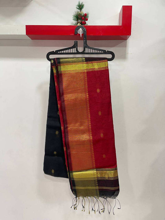 Colorful scarf with black border on a hanger against a white wall.
