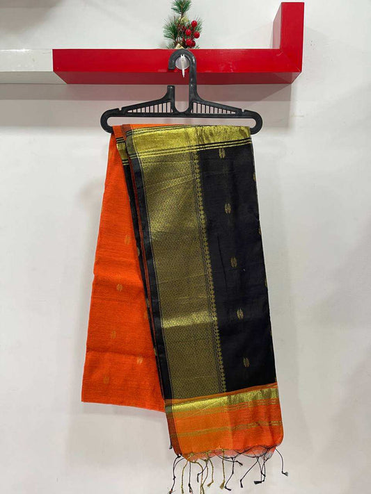 Saree with orange, green, and black patterns hanging on a red shelf.