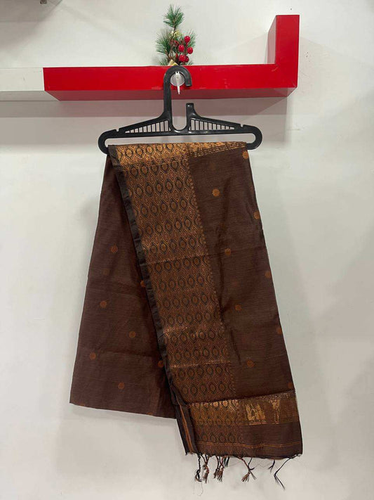 Brown patterned scarf on a hanger against a white wall with a red shelf above.
