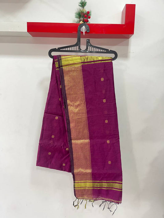 Purple saree with gold border on a hanger against a white wall.