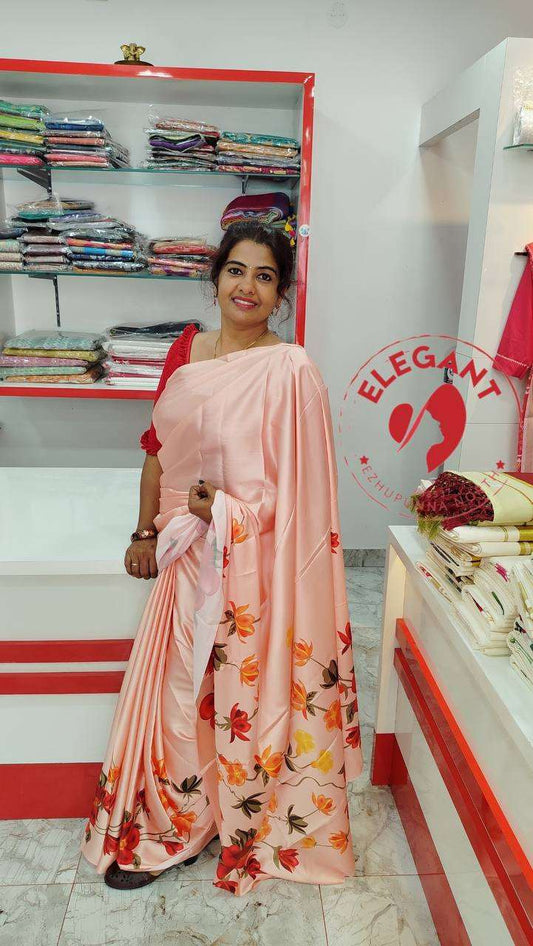 Woman wearing a peach satin silk saree with floral print standing in a fabric store showcasing elegant satin silk sarees for occasion and party wear.