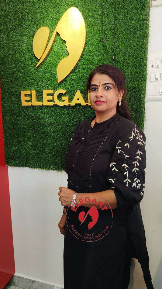 Woman wearing black Kurthi Set with white embroidery standing in front of green wall with Elegant logo