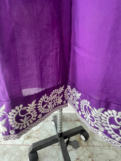 Purple fabric with white embroidery draped over a chair on a tiled floor.
